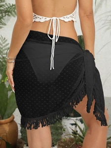 Dettaglio di gonna da spiaggia a portafoglio in rete nera con pois e frange boho