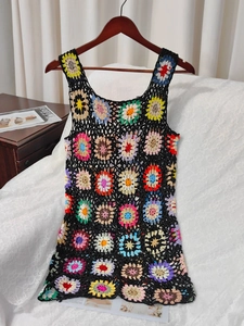Dettaglio di mini abito all'uncinetto fatto a mano con fiori colorati su fondo nero