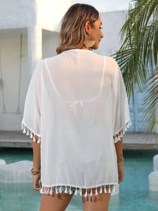 Vue détaillée du dos d'un cache-maillot en mousseline blanche avec pompons à la piscine