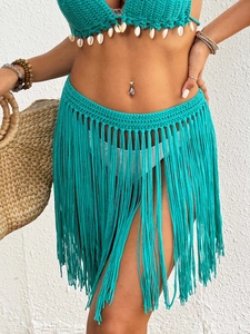 Detail of turquoise crochet bikini set with white shells and long fringe hem skirt