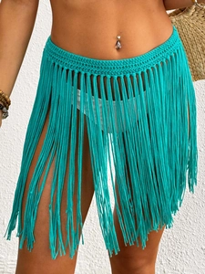 Detailed close-up of handmade crochet fringe beach skirt with hollow knit pattern in green