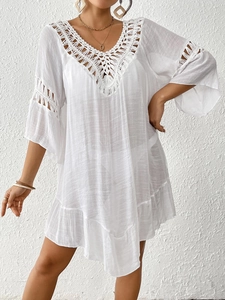 Detail of bohemian beach cover-up featuring intricate crochet V-neck and flared sleeves