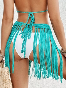 Detail of turquoise crochet beach cover-up featuring hand-knit fringe and tie-waist