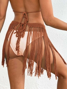 Close-up of handmade crochet texture and long fringe tassels on a brown wrap skirt