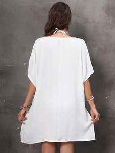 Rear view of white loose beach cover-up dress featuring a halter neck tie and crepe fabric