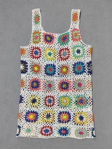 Dettaglio del gilet all'uncinetto boho con motivi mandala floreali colorati su bianco