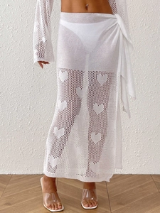 Detail of white crochet beach skirt with heart patterns and side tie closure