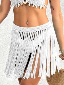 Detail of crochet fringe skirt with shells and boho white knit textures for beach wear