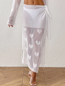 Detail of white crochet heart pattern knit beach skirt with side tie wrap sarong design