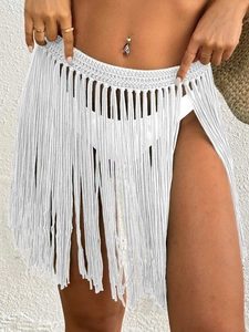 Close-up detail of white crochet lace waist and long fringe tassels beach cover-up skirt