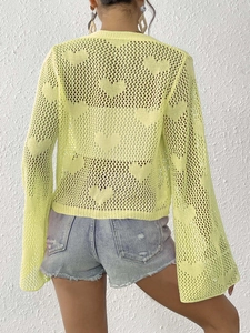 Close-up of heart crochet pattern and bell sleeves on a yellow knit cardigan top