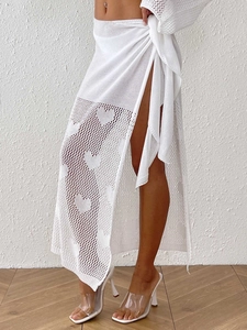 Detail of white knit beach cover-up skirt featuring heart patterns and side-tie closure