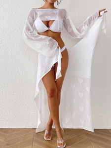 Detail of white crochet beach set featuring hollow heart knit pattern and fringe ties
