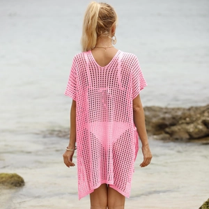 Rear view of a pink hollow-out crochet beach cover-up dress against a seaside background