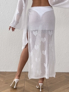 Detail of white knit beach cover-up skirt with intricate heart-shaped hollow-out patterns