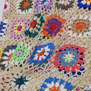 Dettaglio ravvicinato di maglia fatta a mano all'uncinetto con motivi floreali colorati