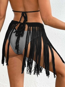 Detail of hand-crocheted black wrap skirt featuring long tassels and woven tie closure