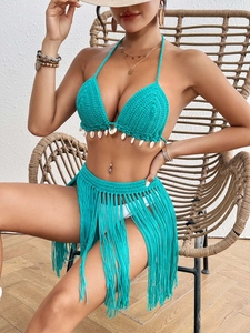 Detailed close-up of handmade crochet bikini set with shell fringe and tassel skirt