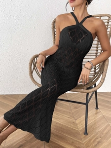 Detail of black crochet knit beach dress with leaf pattern cutouts and halter neck
