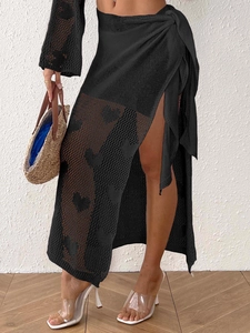Detailed macro view of black crochet beach skirt with hollow heart patterns and side tie