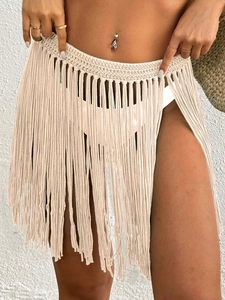 Detail of beige crochet beach cover-up skirt with intricate tassels and woven waistband