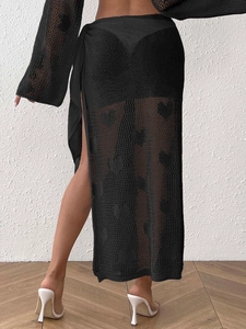 Detail of black crochet beach skirt with heart pattern weave and elegant side slit