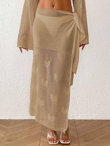 Detailed knit pattern of beige crochet beach cover-up with woven heart motifs