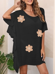 Detail of black beach cover-up featuring 3D floral appliques and ruffled sleeves