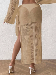 Detail of beige crochet beach skirt featuring heart openwork pattern and side tie waist