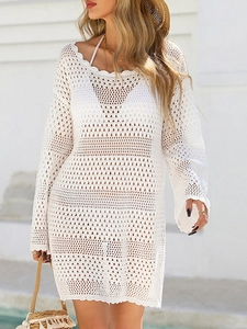 Detail of white crochet beach cover-up showing wavy hollow knit patterns and V-neckline