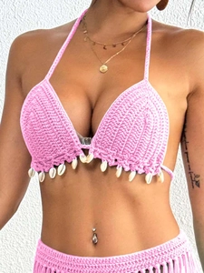 Macro shot of pink handmade crochet bikini top with hanging white seashell details