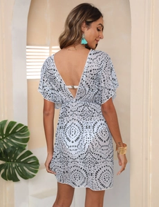 Dettaglio vestito da spiaggia bianco a pois con profondo scollo a V e gioielli boho