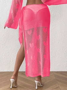 Detailed close-up of neon pink knit beach skirt featuring heart-shaped openwork patterns