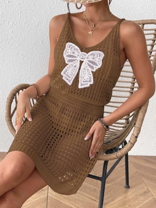 Details der Stricktextur des braunen Häkelkleids mit weißer Spitzen-Schleife