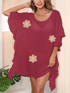 Detail of burgundy beach cover-up featuring textured fabric and floral applique with beads