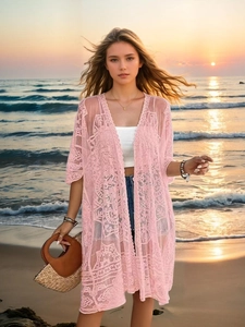 Detailed view of pink floral lace cardigan with semi-transparent embroidery at sunset