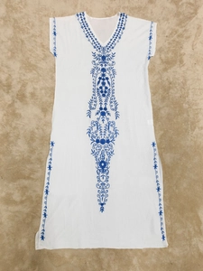 Détails de broderie sur une robe de plage blanche à col en V avec motifs floraux bleus en coton
