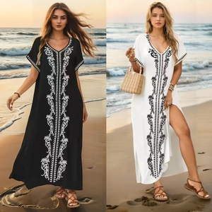 Detail of bohemian maxi beach dresses in black and white with vintage floral embroidery