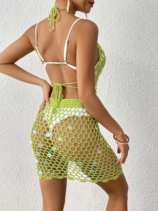 Detail of green crochet mesh mini skirt featuring iridescent sequins for beach vacation