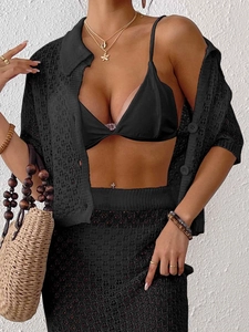 Detail eines schwarzen Häkelstrick-Kurzarmshirts mit V-Ausschnitt und drei Knöpfen