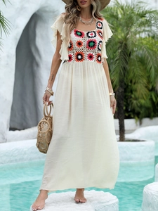 Detail of bohemian crochet floral patchwork and ruffled sleeves on white beach dress