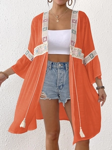 Dettaglio di kimono boho arancione con bordi in pizzo e ricami floreali colorati