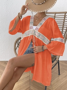Dettaglio del copricostume arancione con inserti in pizzo bianco e ricami floreali