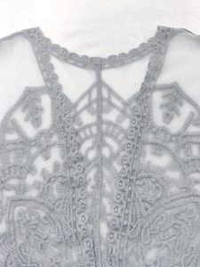 Close-up of delicate lace embroidery and scallop trim on sheer bohemian cardigan