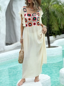 Detail of crochet floral bodice with ruffled sleeves on a white boho beach maxi dress