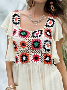 Detail of bohemian crochet top featuring multicolored floral patches and ruffled short sleeves
