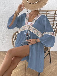 Dettaglio di un copricostume blu bohémien con pizzo bianco e ricami floreali vivaci