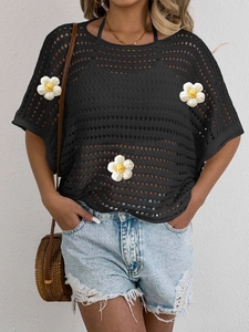 Detail of black crochet top featuring three-dimensional white floral appliques and textures