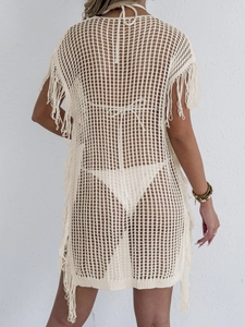 Detail van crèmekleurige gehaakte strandoutfit met opengewerkt patroon en lange franjes