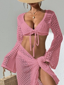 Détail de la texture en maille crochet rose sur haut de plage à manches longues et lacé
